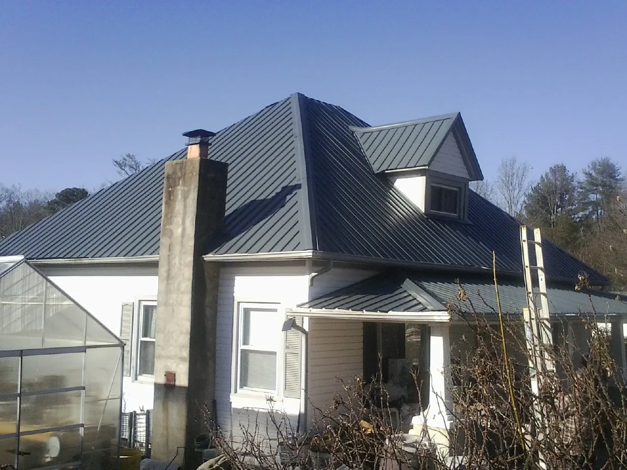 Dark blue standing seam metal roof on a white farmhouse with dormer — Slate & Tile Roof Repair by Roofing Brothers in Whately