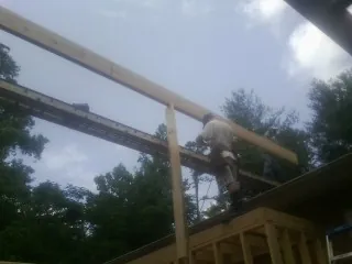 Carpenter setting a ridge beam over a new addition frame — Ice Dam Removal by Roofing Brothers in Whately