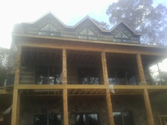 Dormers and porch framing on a large log home under construction — Roof Coating work by our crew in Whately