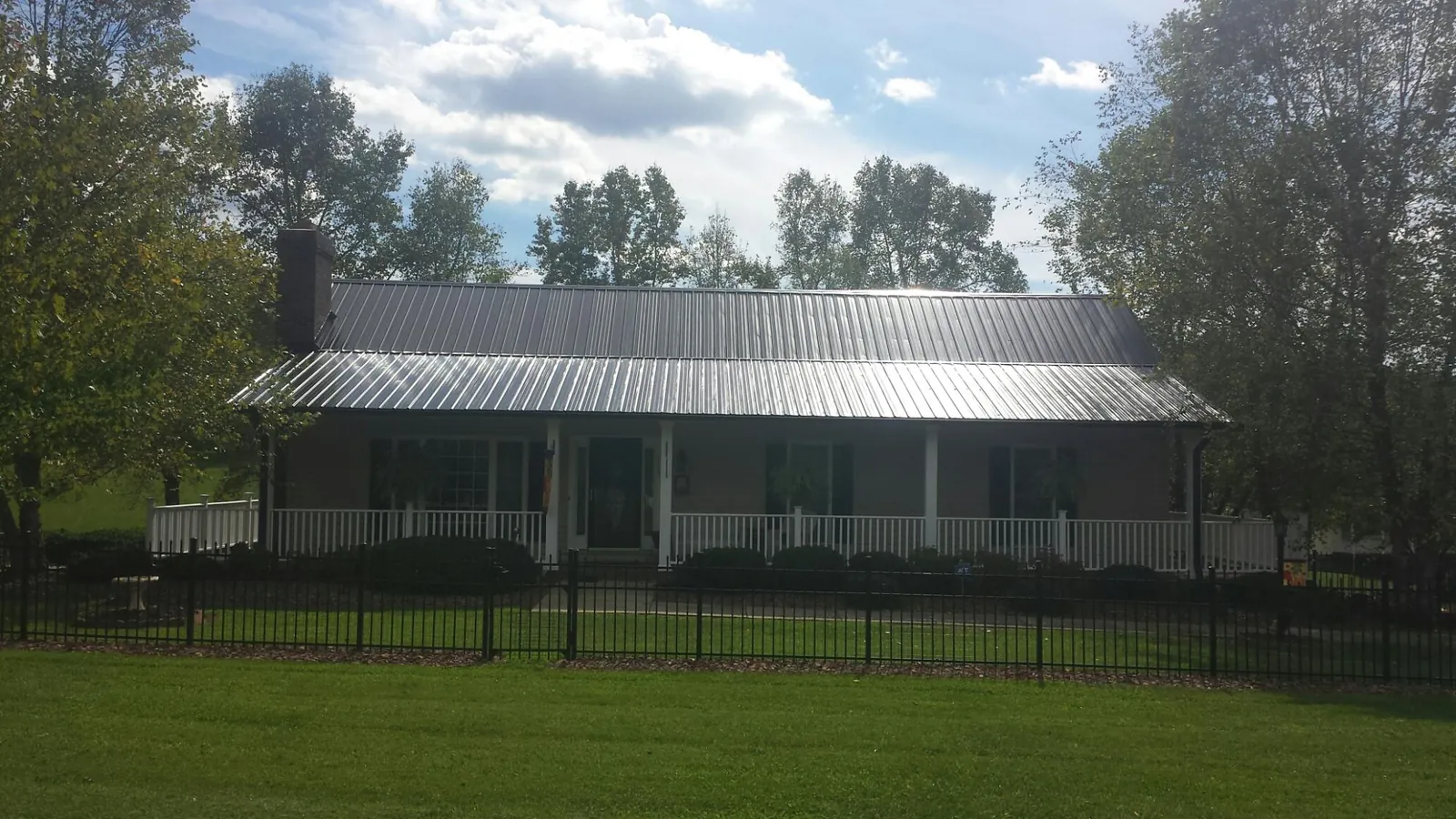 Gray metal roof on a brick ranch with a full width front porch — Gutter Guard Installation work by our crew in Whately