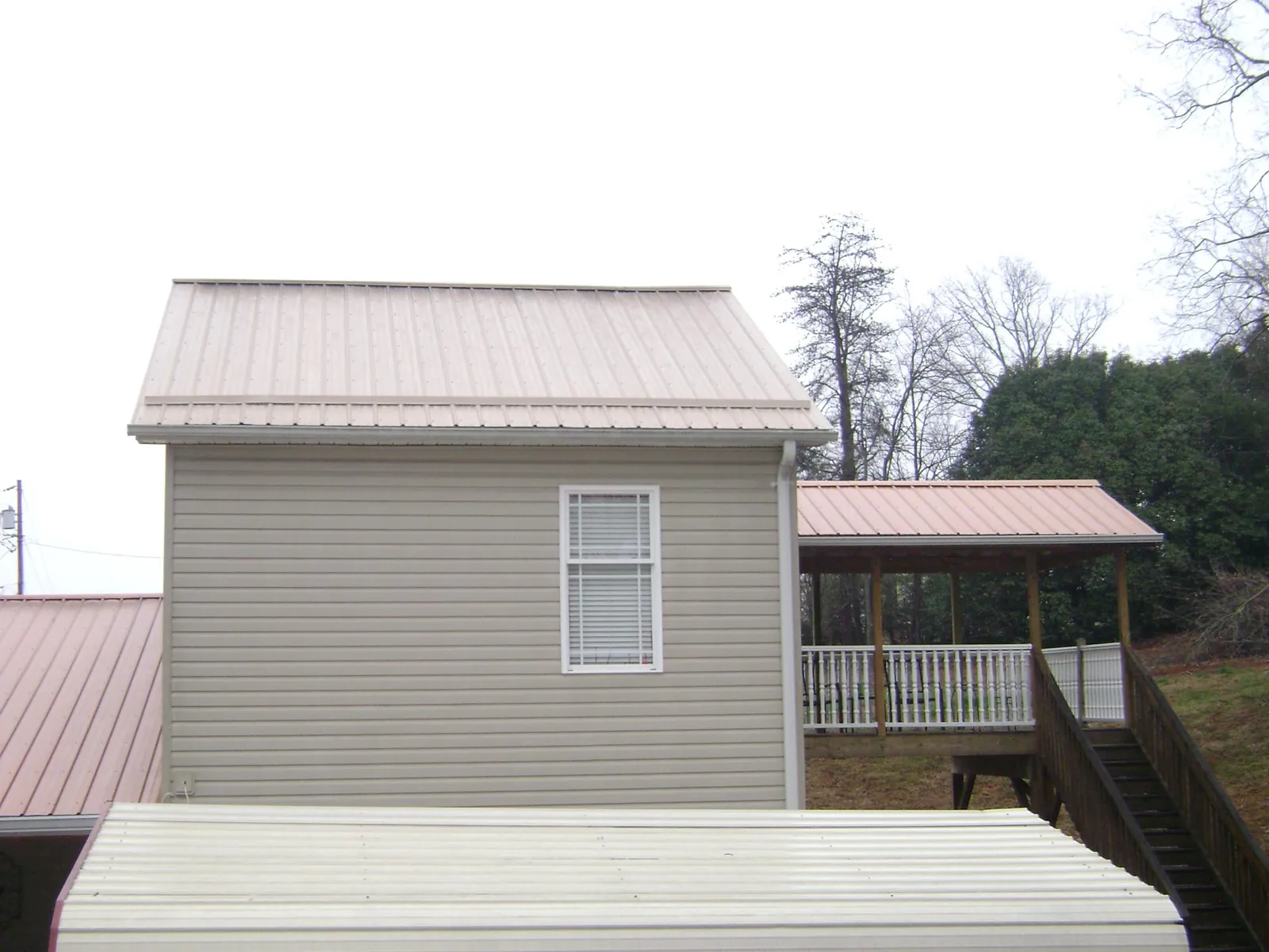 Tan metal roofs on a two story addition and attached porch, from a Roof Replacement job in Whately