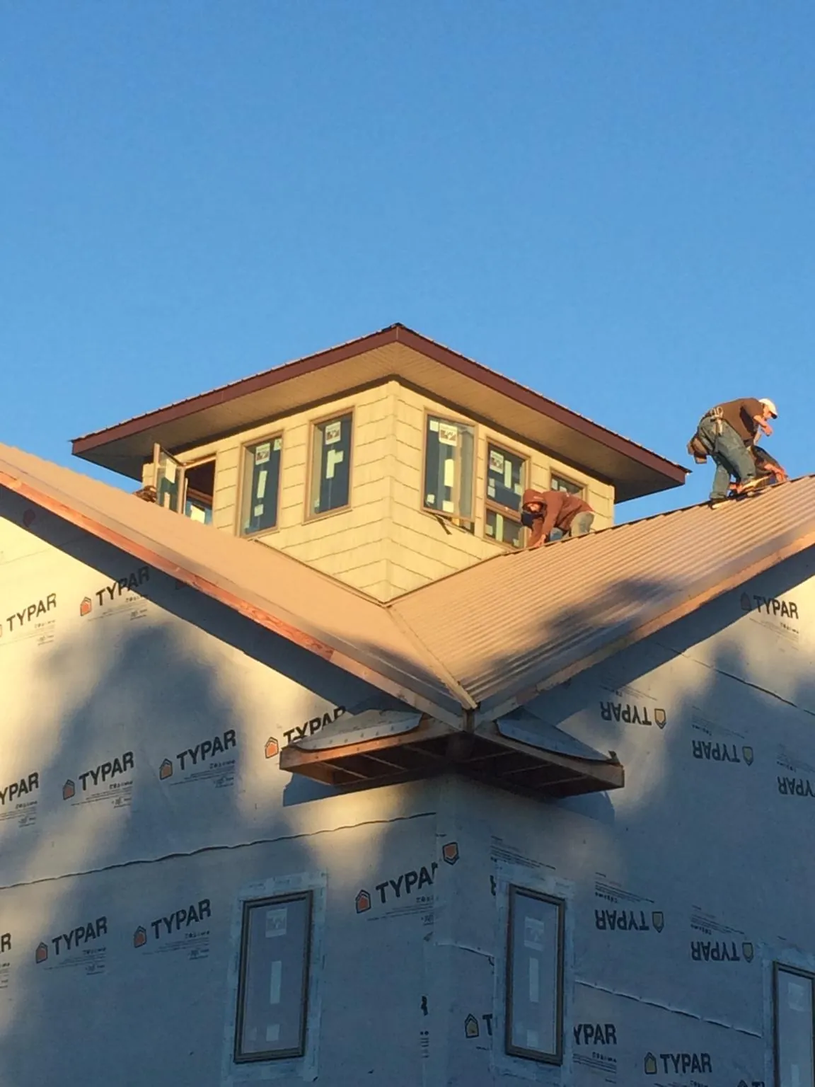 Roofers working around a rooftop cupola on a new metal roof at sunset — Roof Waterproofing in Whately by Roofing Brothers